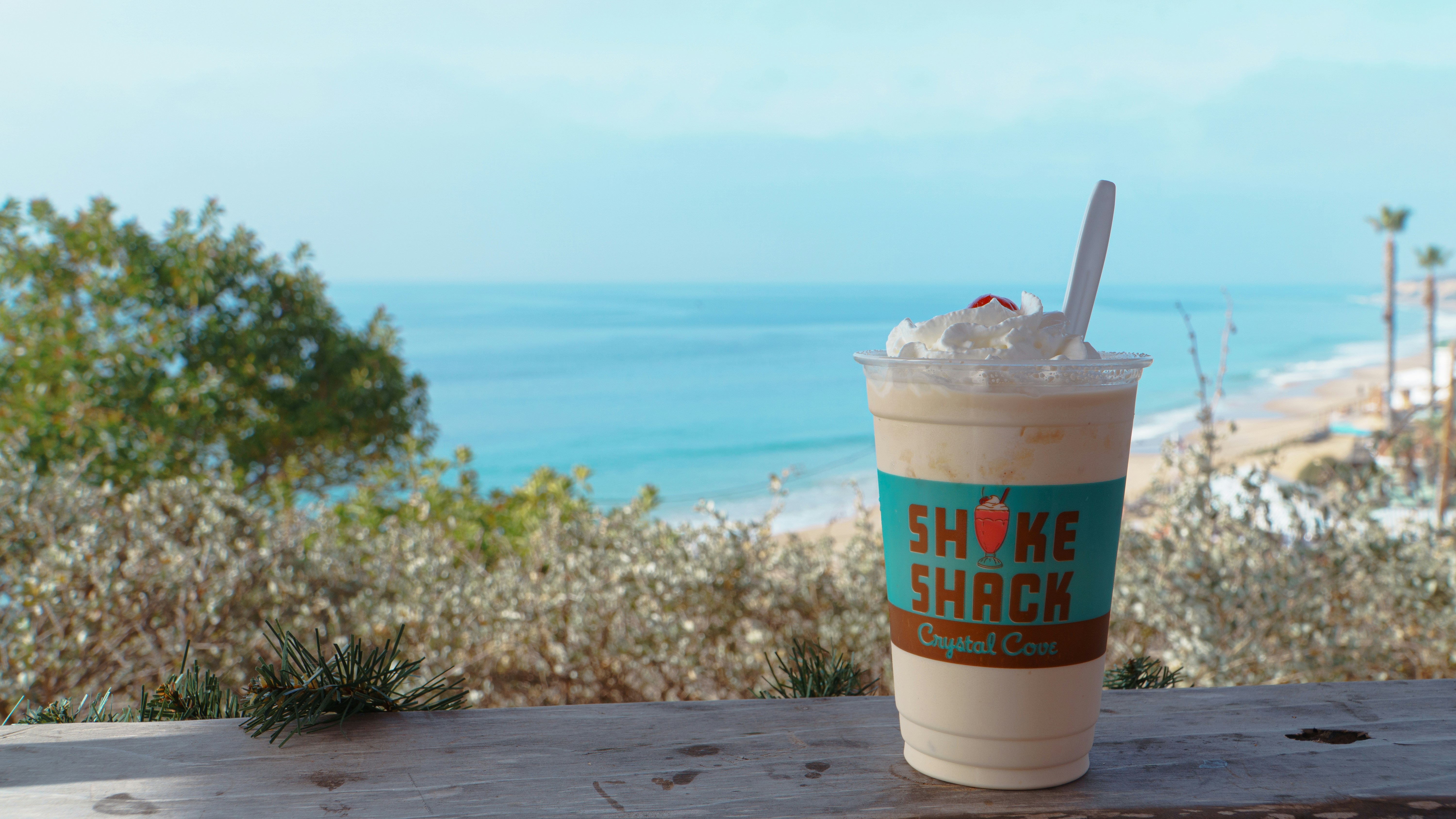 Milkshake with whipped cream and toppings on dark wooden table, cozy restaurant atmosphere, warm light