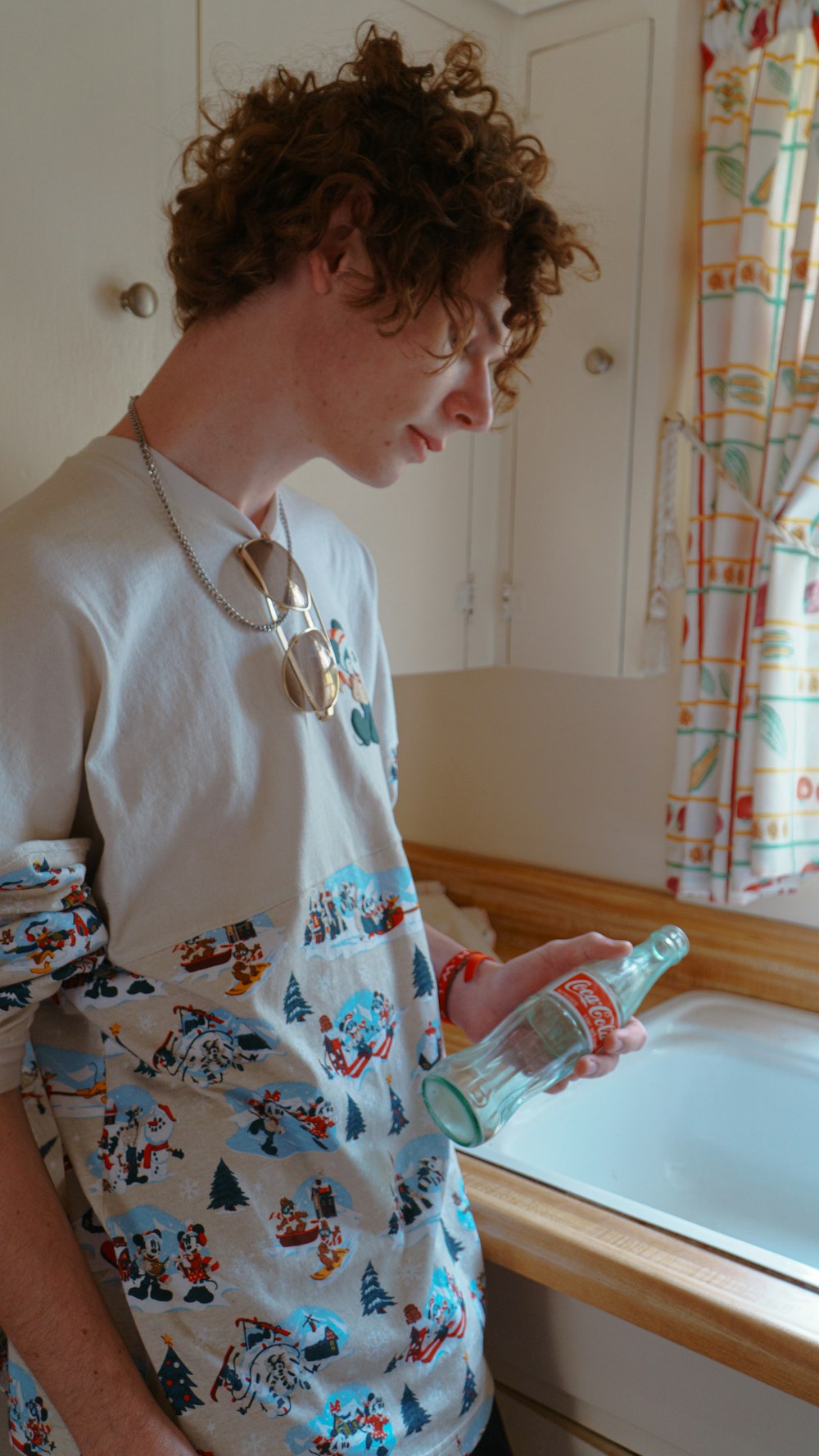 a man standing in front of a sink holding a bottle