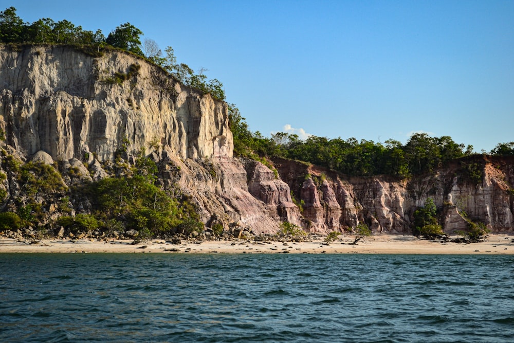 a large cliff on the side of a beach next to a body of water