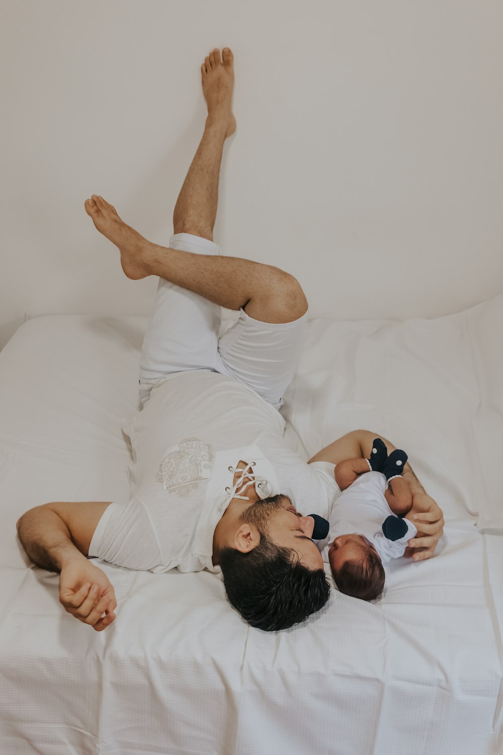 a man laying on top of a bed holding a baby