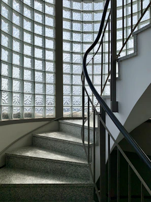 Refined glass balustrade wrapping around a curved staircase, reflecting soft ambient lighting.
