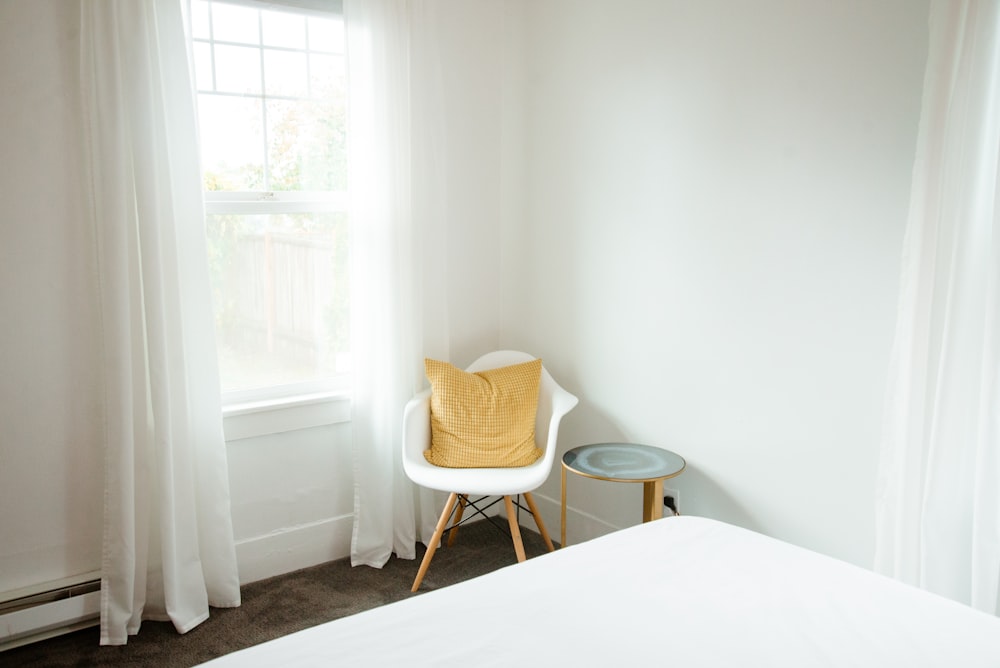 a bedroom with a chair and a window