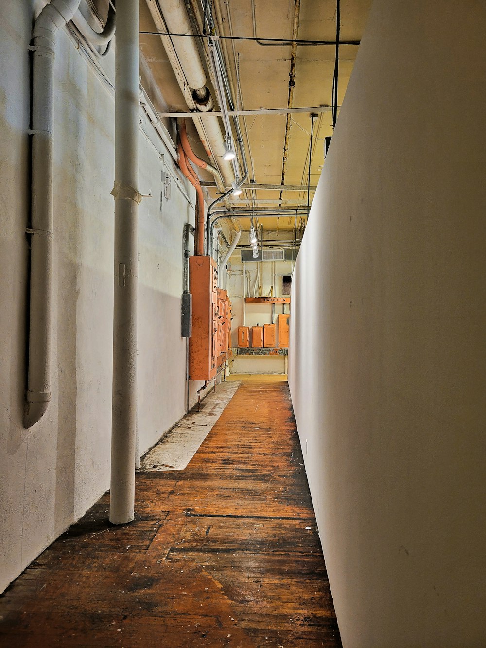 a long hallway with white walls and exposed pipes