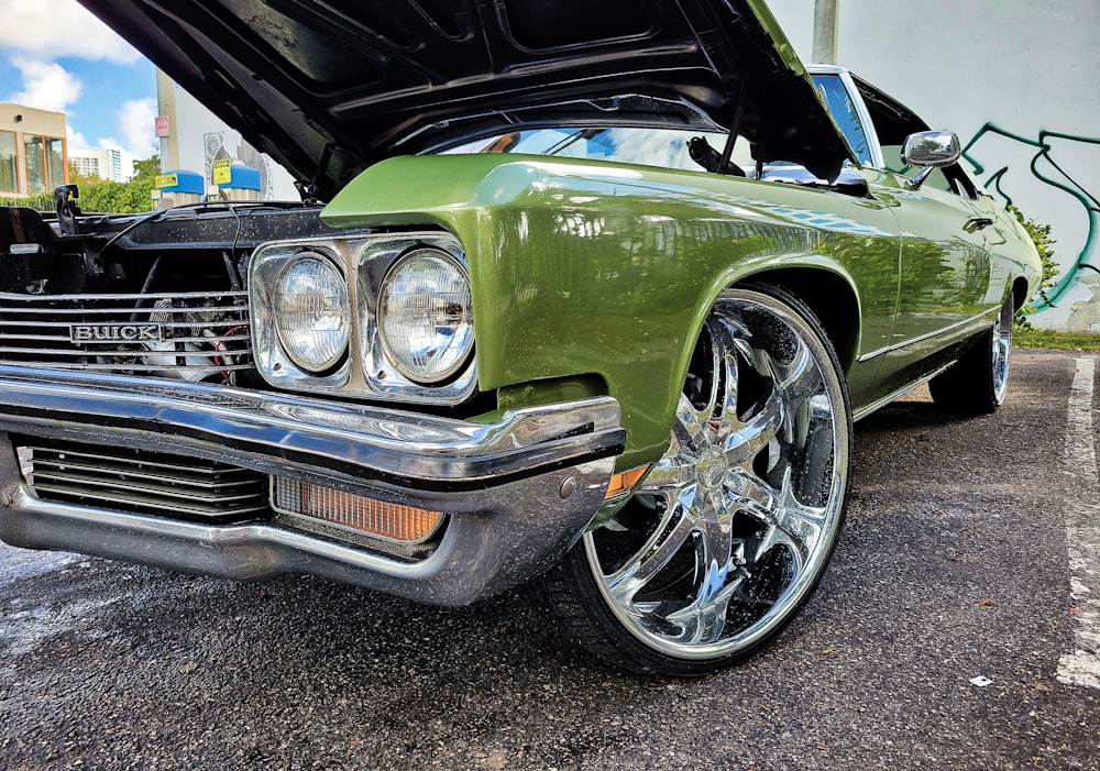 a green classic car with its hood open