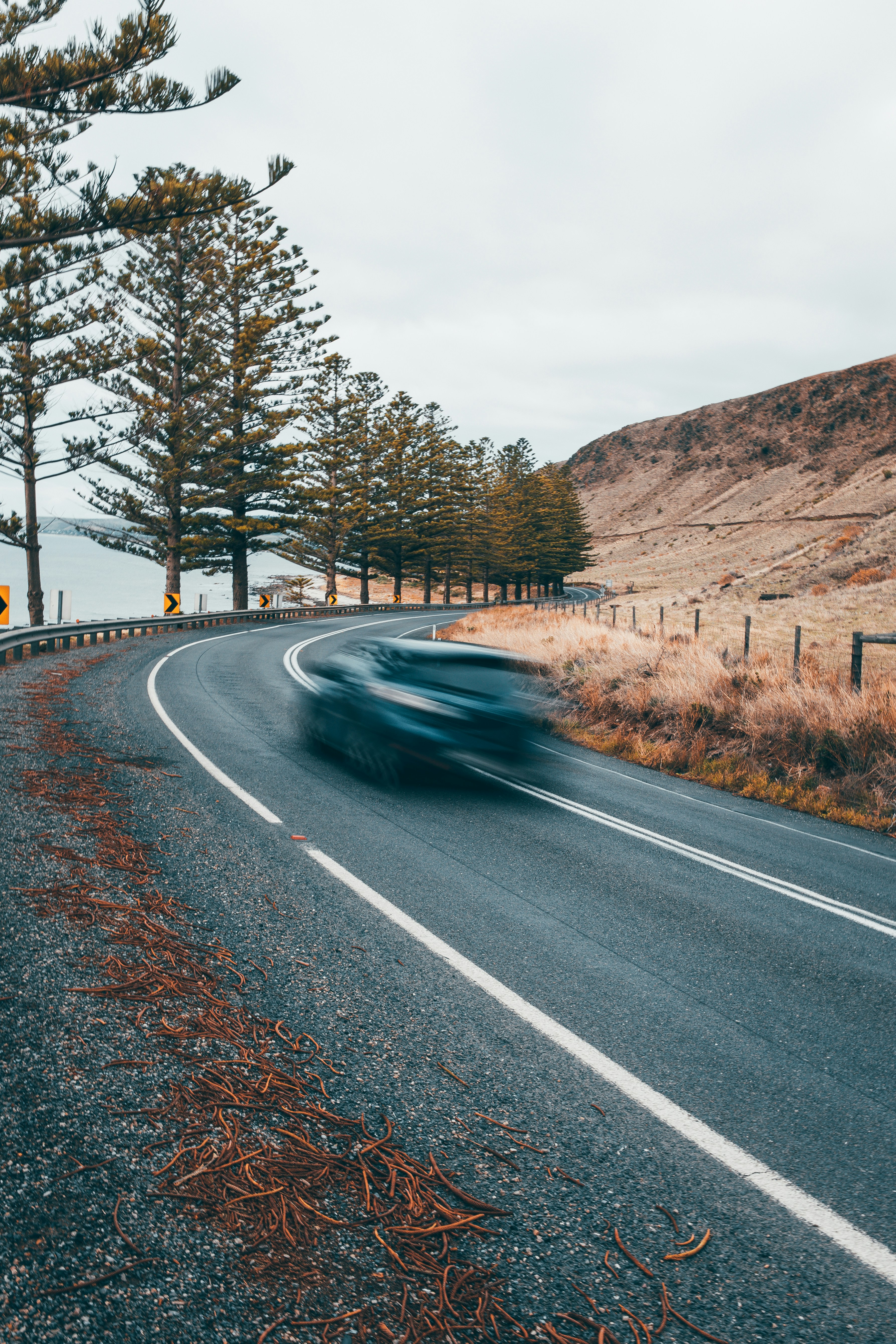 A birds-eye view of a scenic road with a car driving on it.