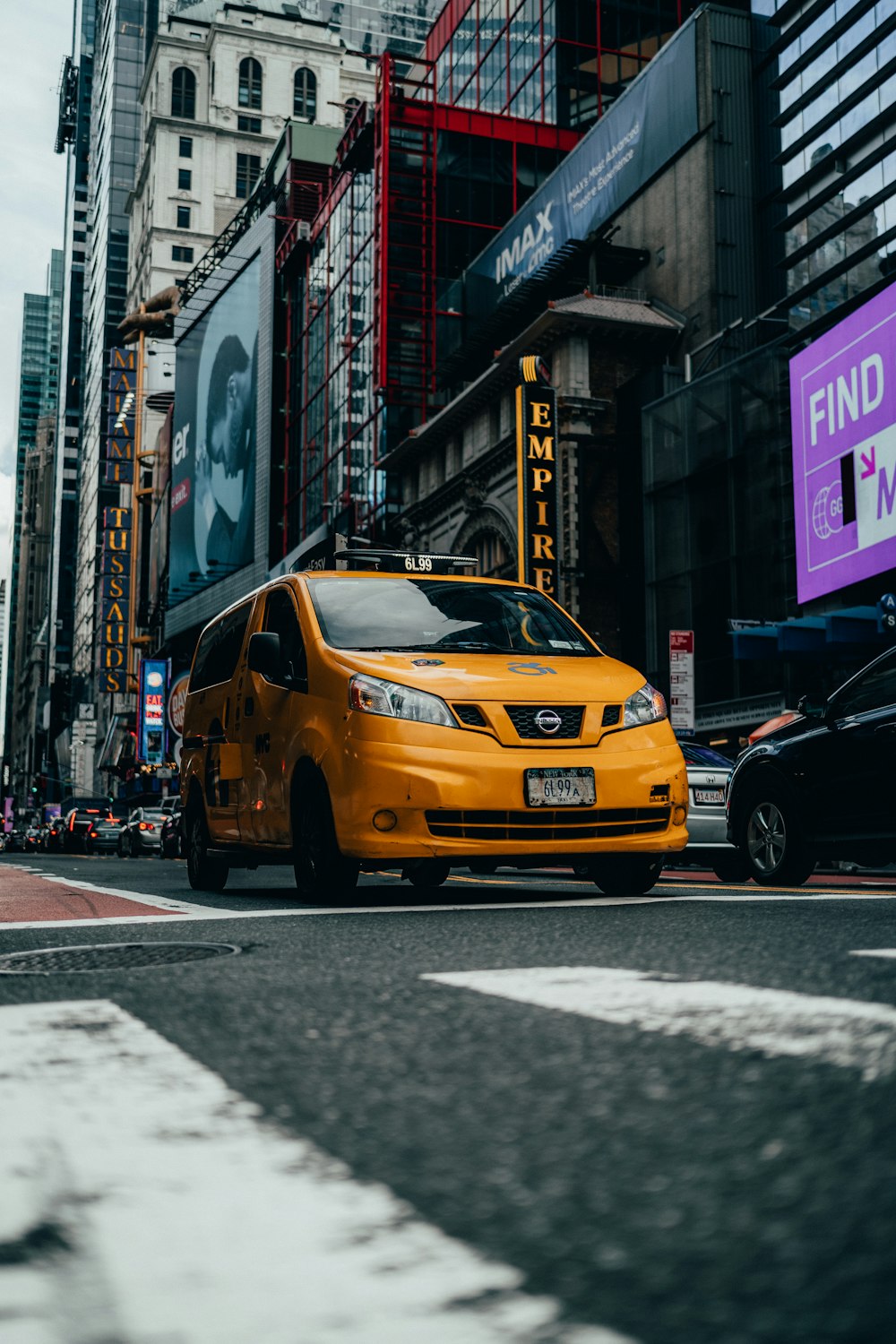 a yellow taxi cab driving down a street next to tall buildings