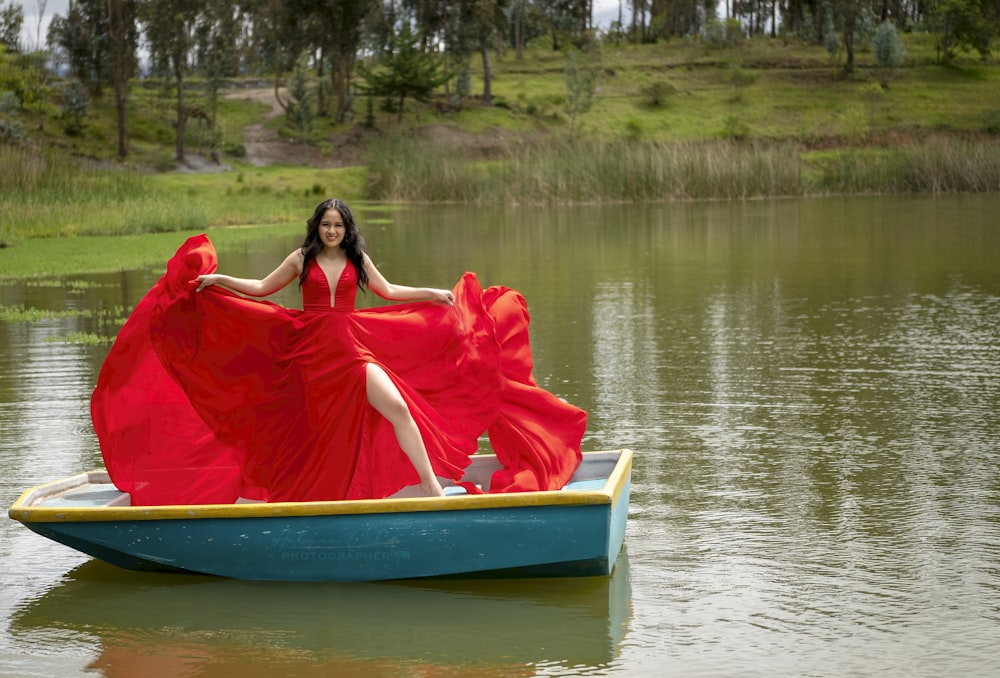 a woman in a red dress sitting in a blue boat