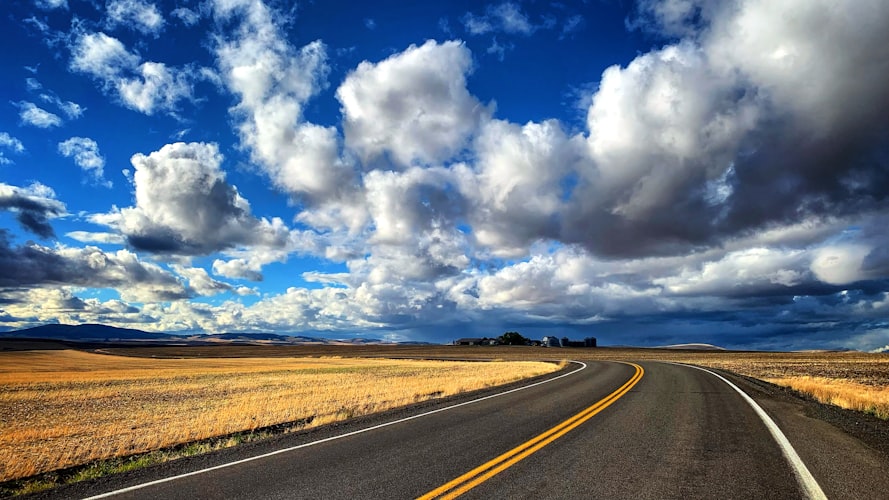 Dramatic clouds over an open prairie road — Coming of Age fiction by J.P. Barelli