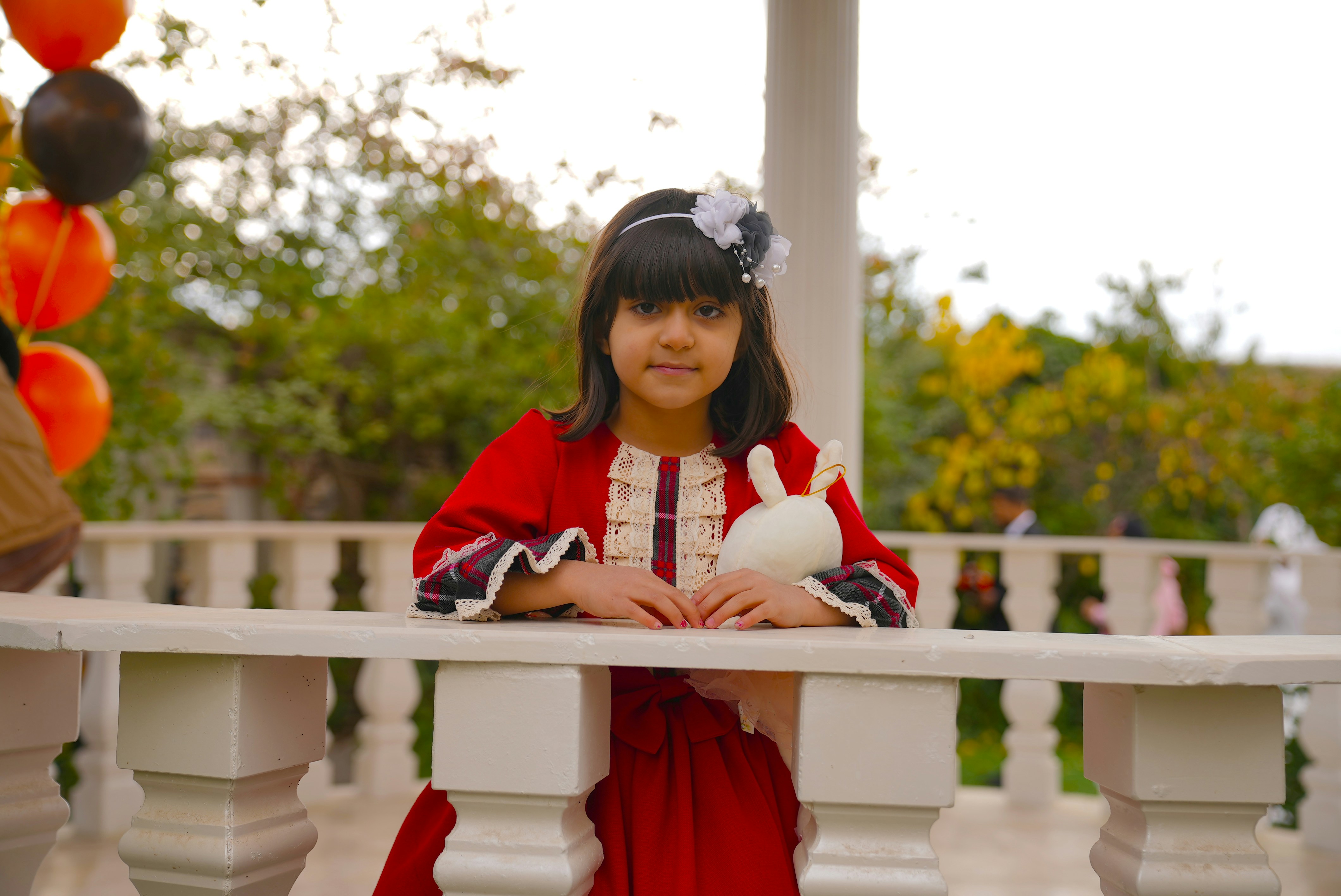 Seorang gadis kecil dengan gaun merah memegang bola putih