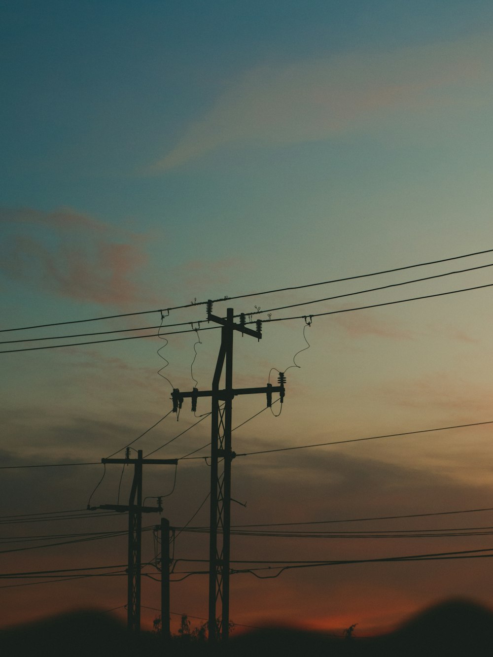 the sun is setting behind power lines and telephone poles