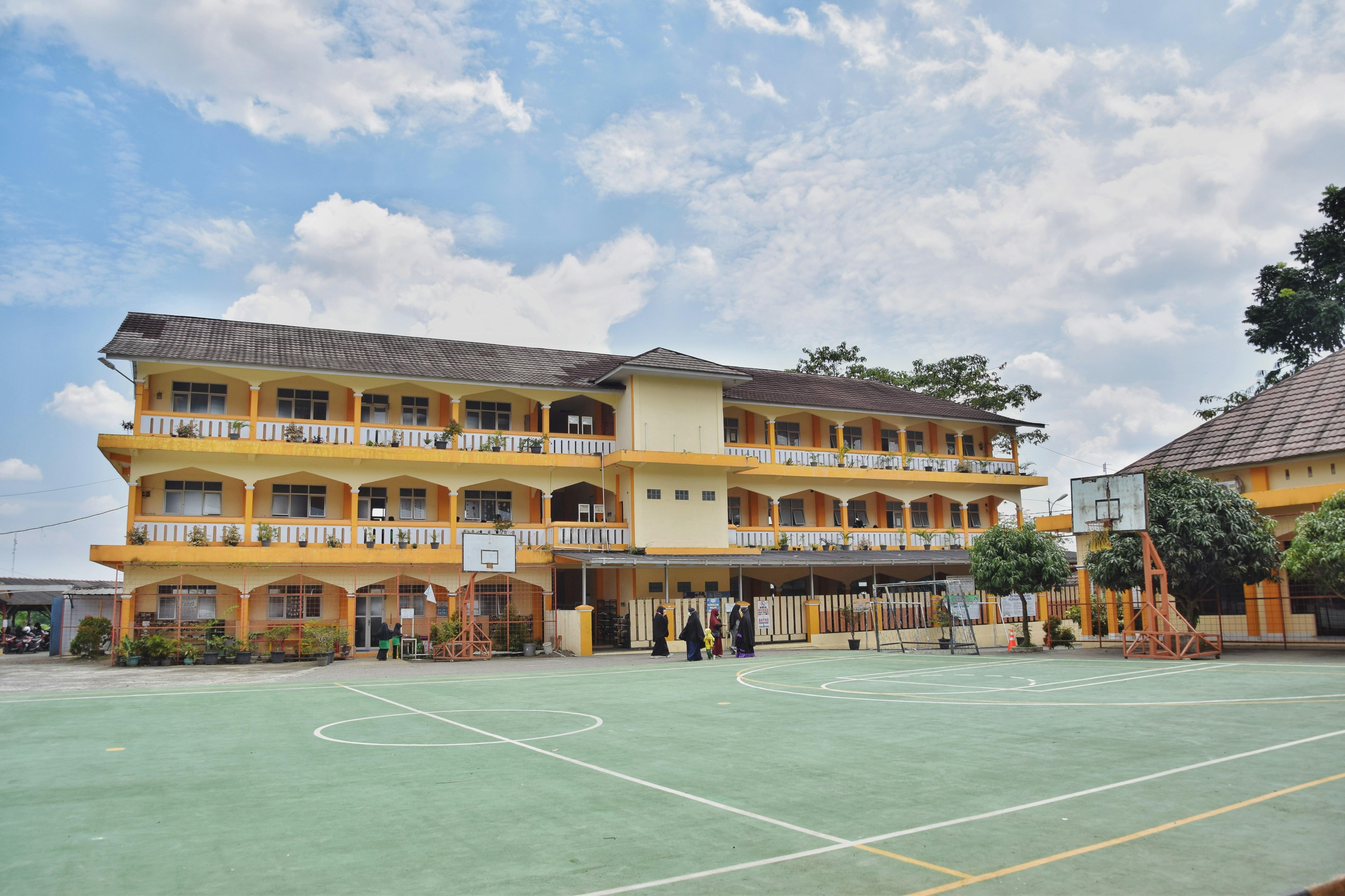 a large yellow building with a basketball court in front of it