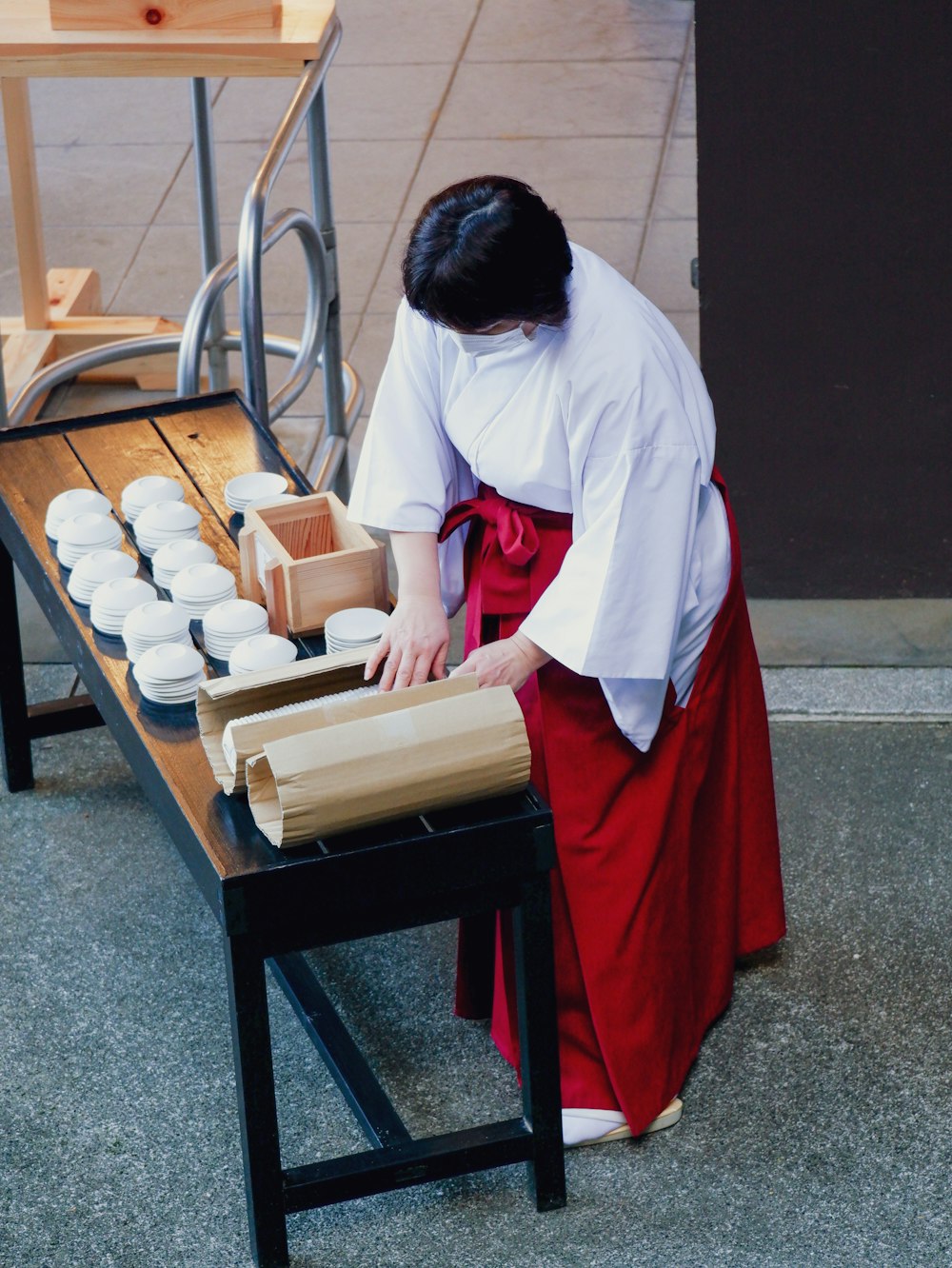 a woman in a white shirt and red skirt standing over a table