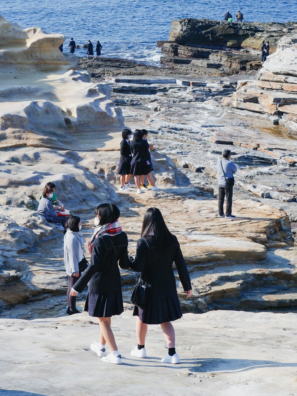 a group of people standing on top of a rocky beach