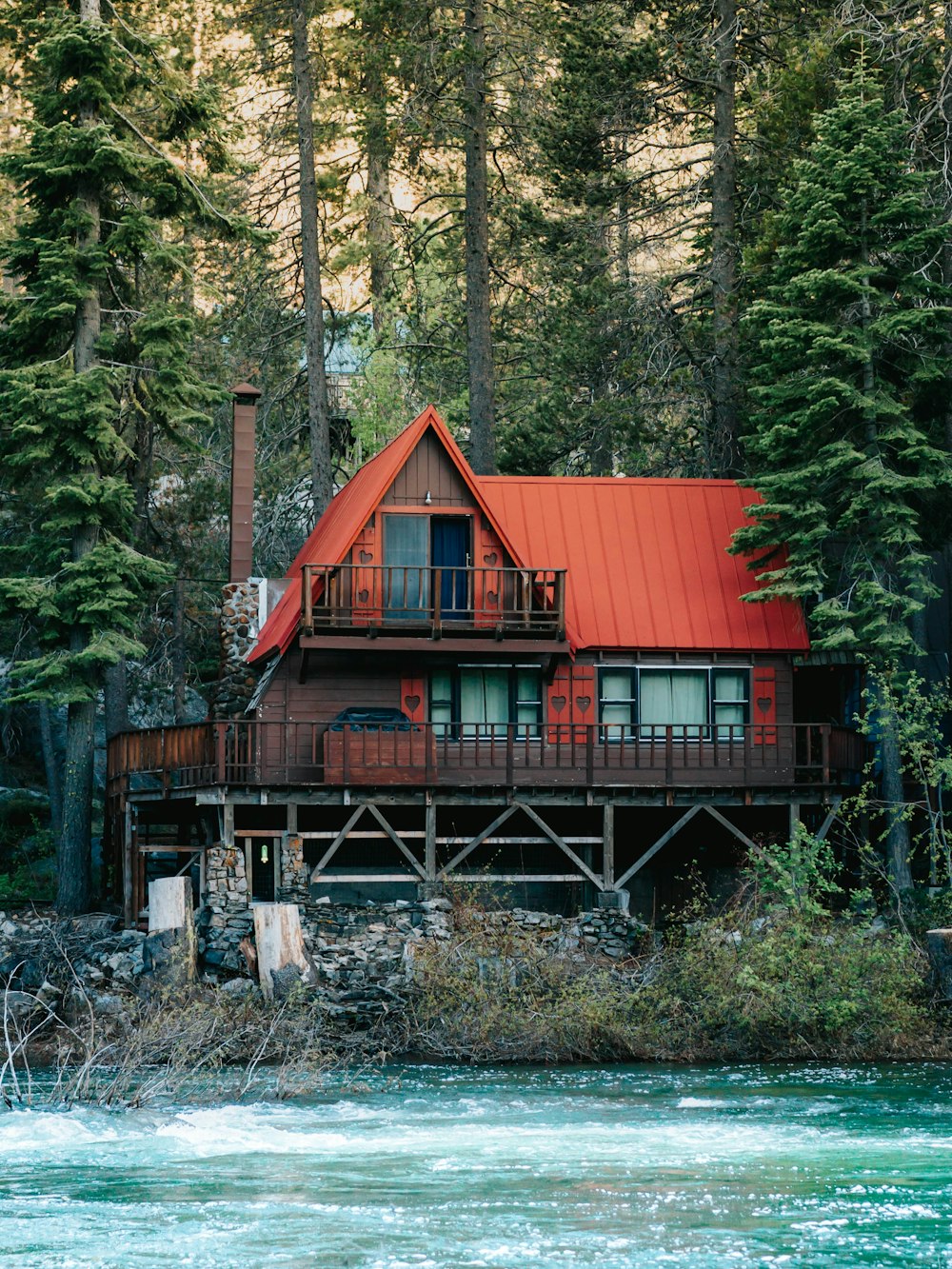 a house with a red roof next to a body of water