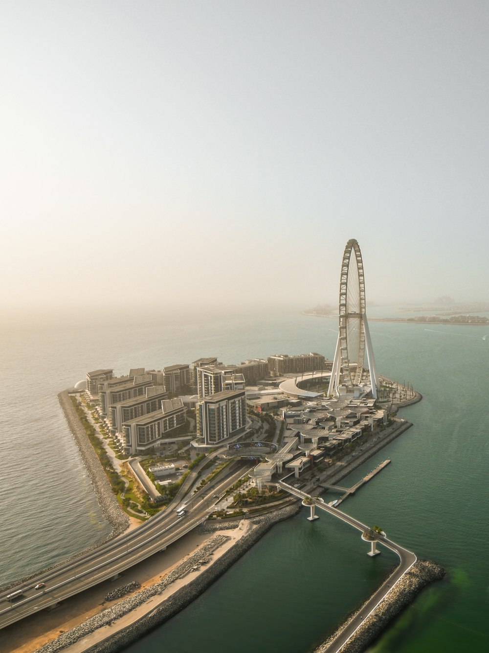 an aerial view of a ferris wheel in the middle of the ocean