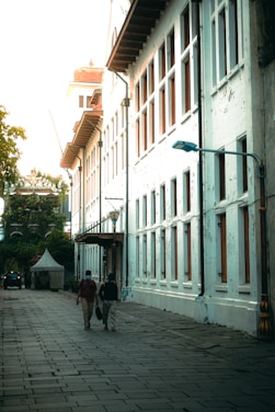 a group of people walking down a street next to tall buildings