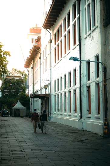 a group of people walking down a street next to tall buildings