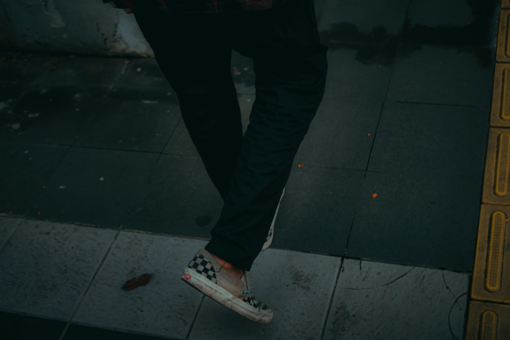 a person standing on a sidewalk with their feet in the air