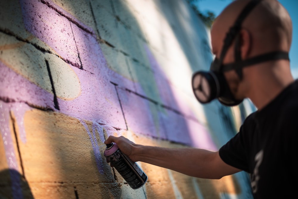 a man spray painting a brick wall with a paint roller