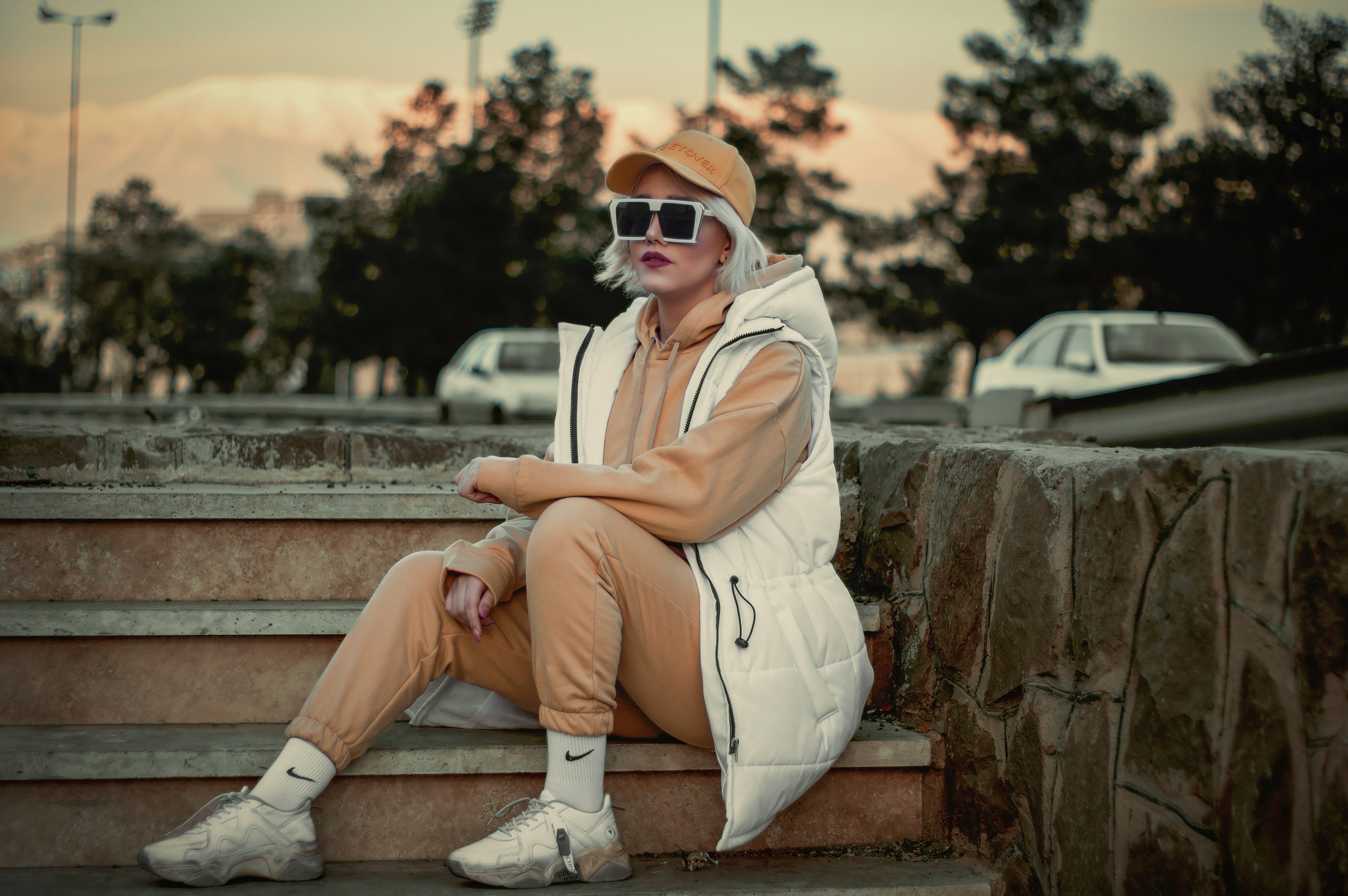 a man sitting on steps wearing sunglasses and a hoodie