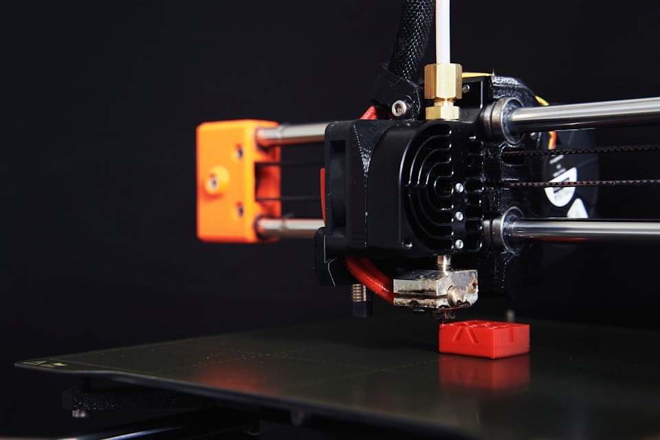 A Prusa Mini FDM 3D printer, printing a red calibration cube