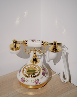 a white and gold phone sitting on top of a wooden table