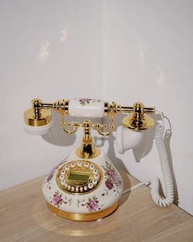 a white and gold phone sitting on top of a wooden table