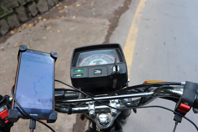 A close-up of a motorcycle dashboard with a GPS tracking device active at dusk.