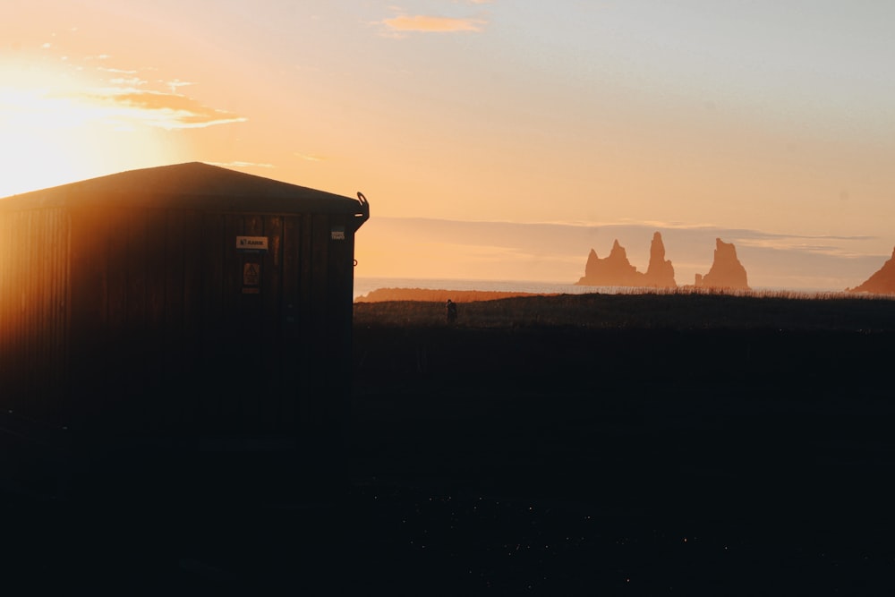 the sun is setting behind a small building