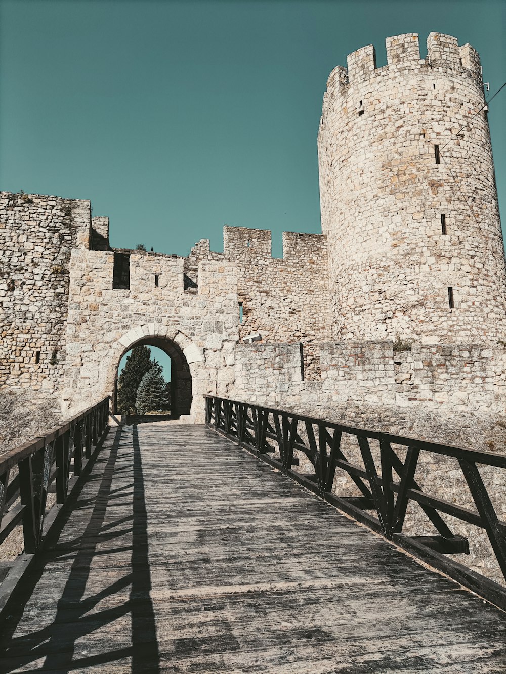 a wooden bridge leading to a stone castle