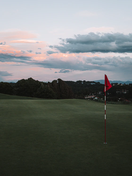 A green and flagstick against the evening sky