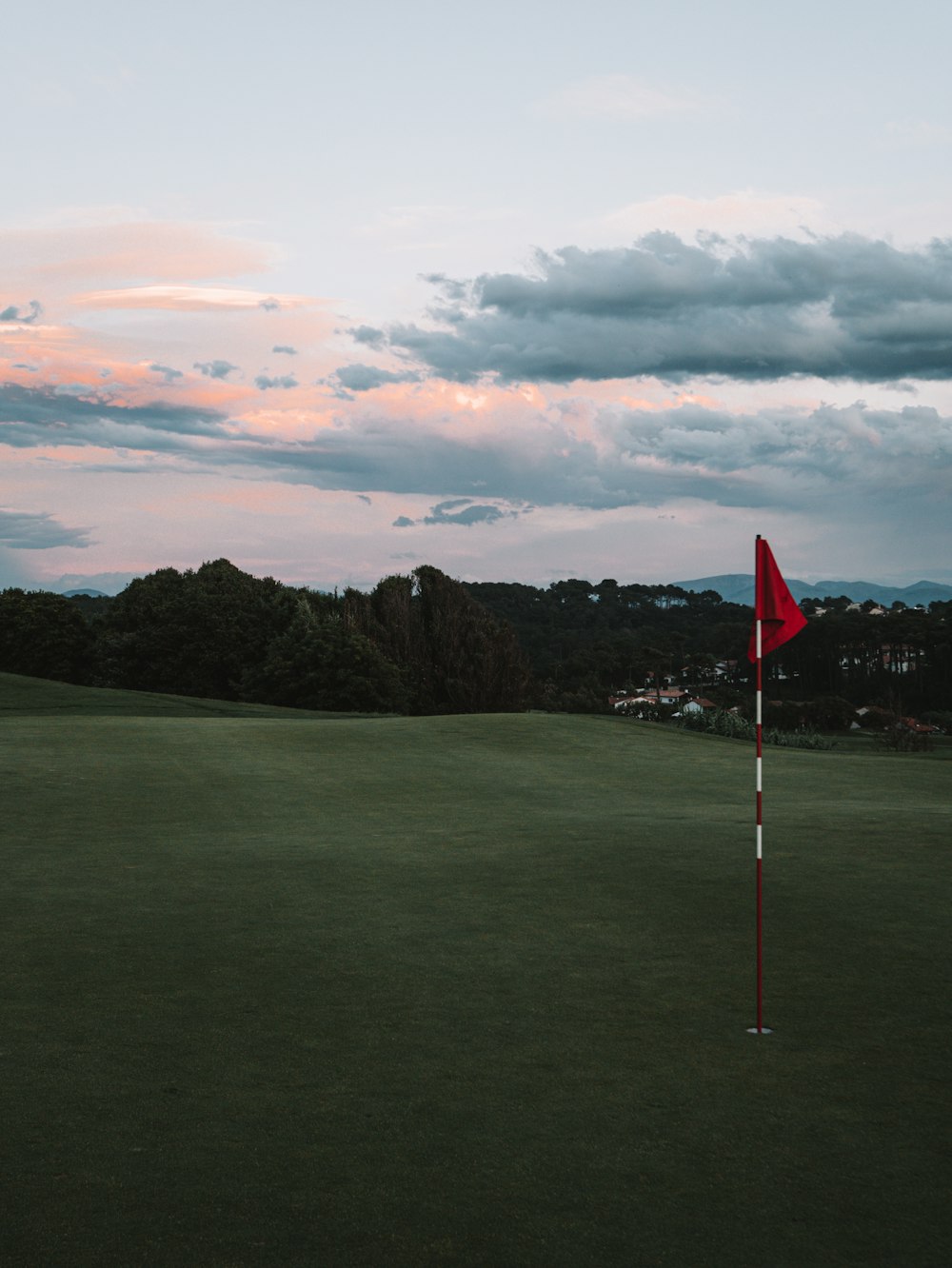 a red flag sticking out of the green of a golf course