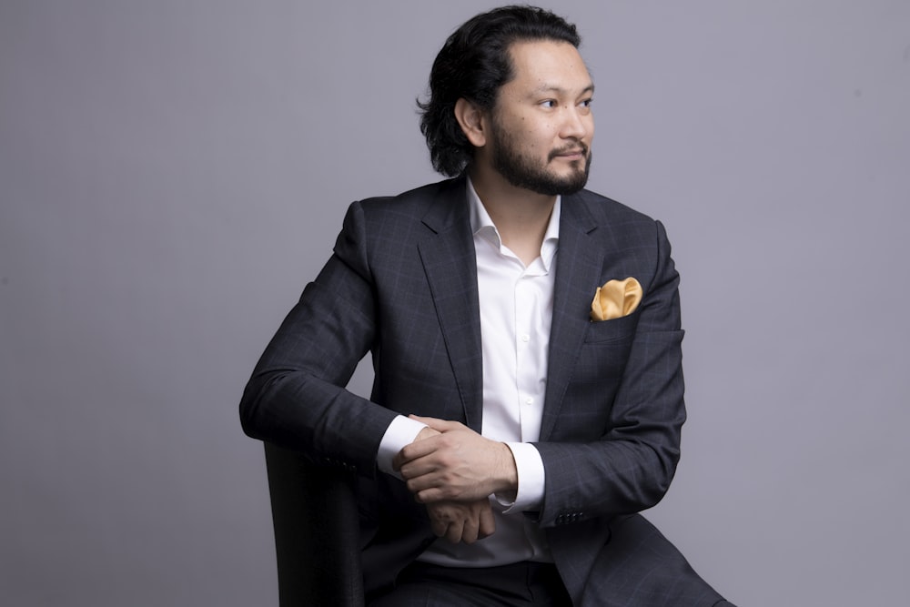 a man sitting in a chair wearing a suit