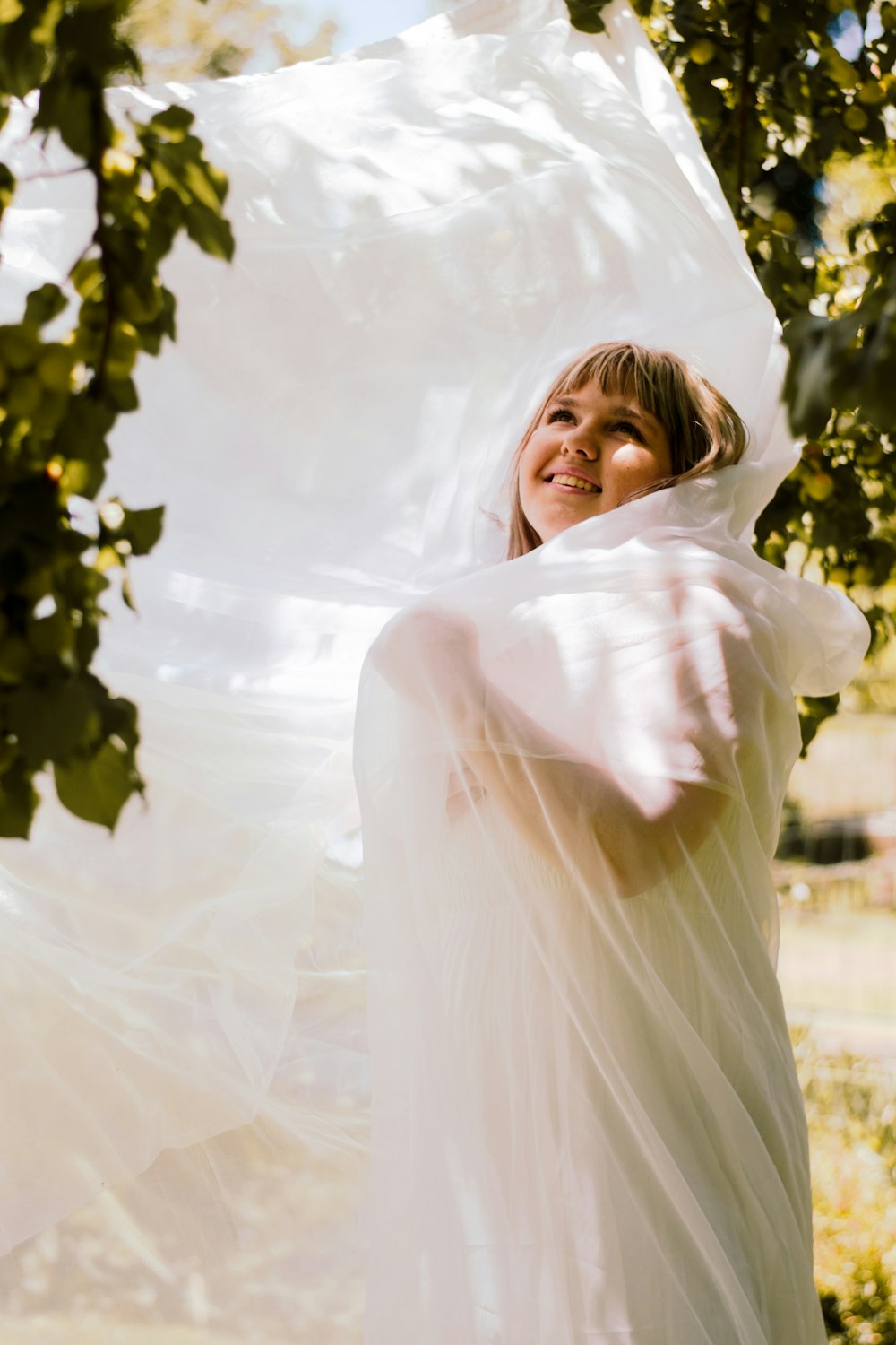 a woman in a white dress holding a white sheet