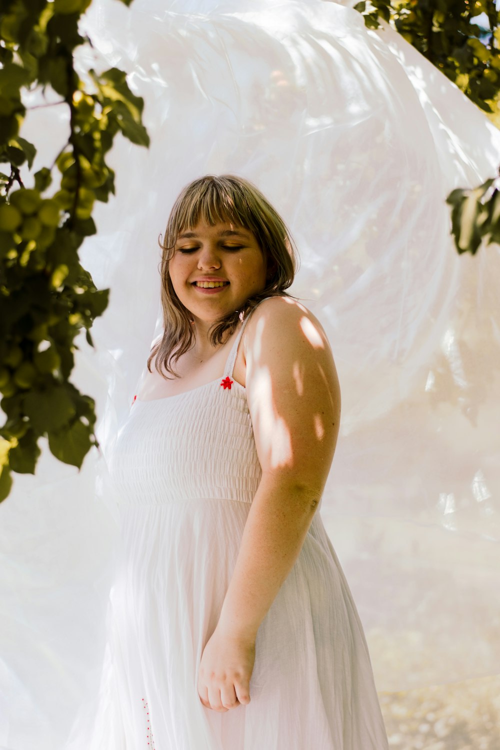 a woman in a white dress standing under a tree