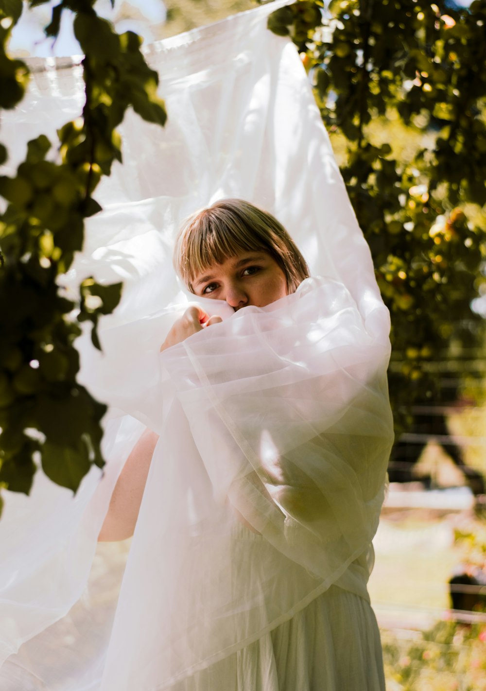 Una donna in un vestito bianco in piedi sotto un albero