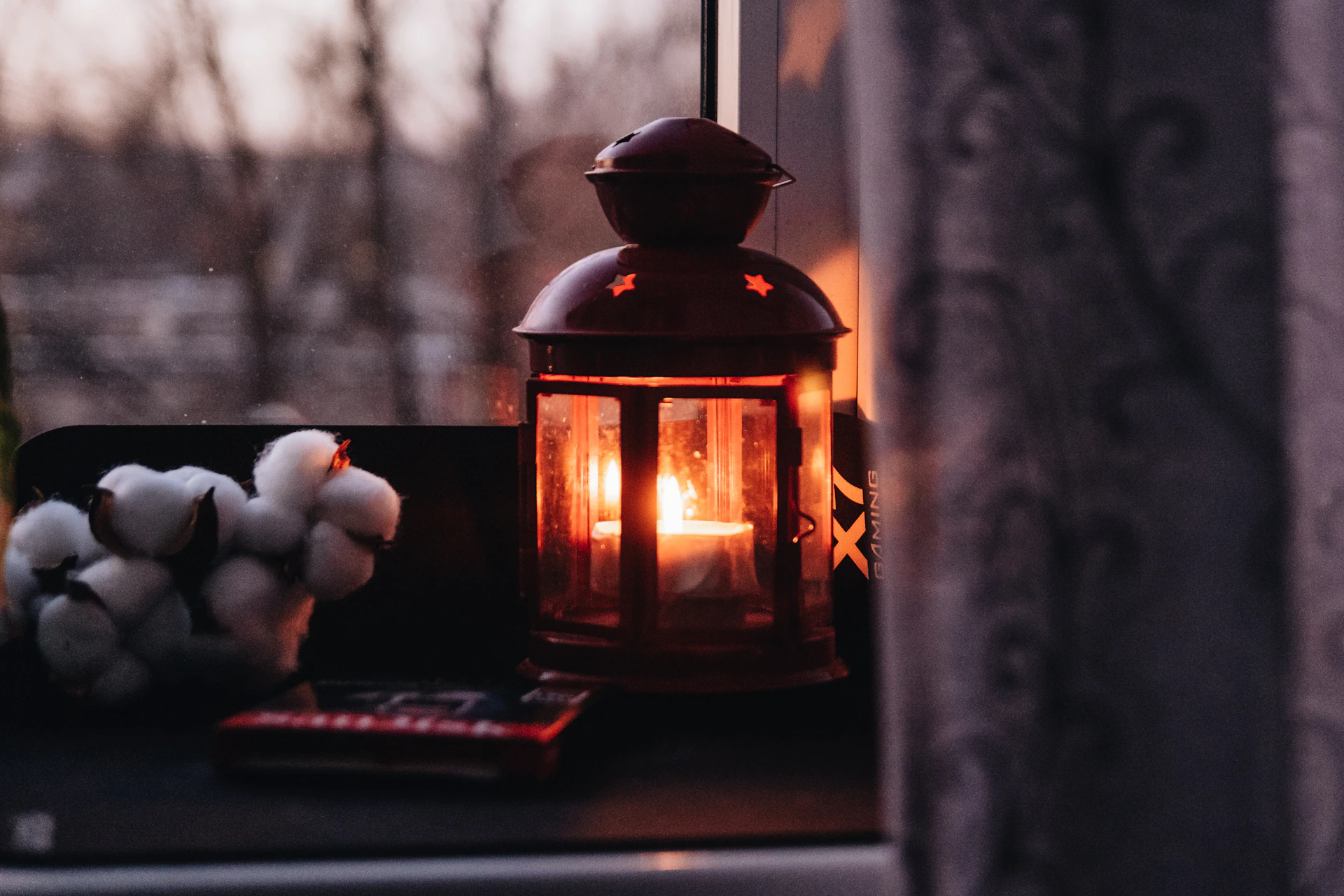 a lit candle sitting on top of a window sill