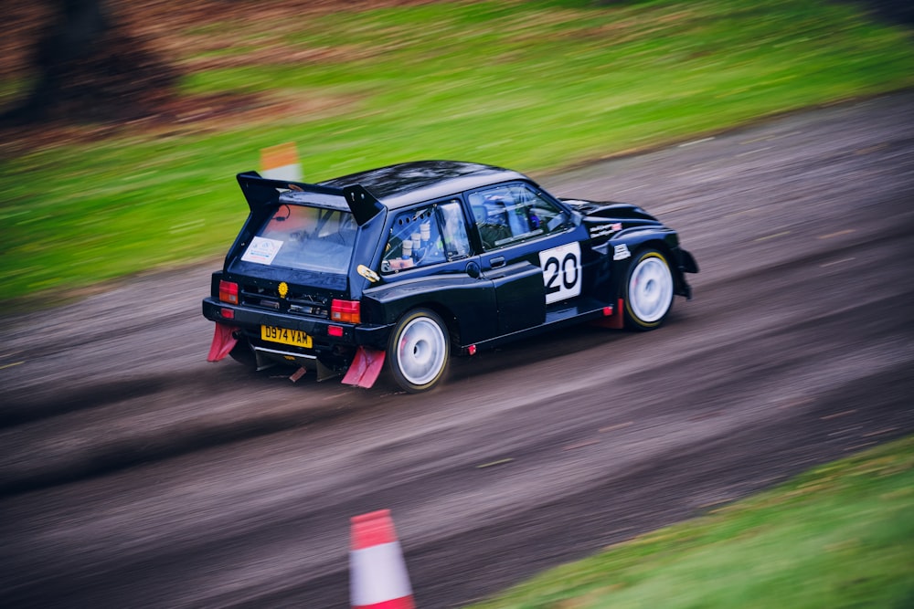 a black car driving down a dirt road