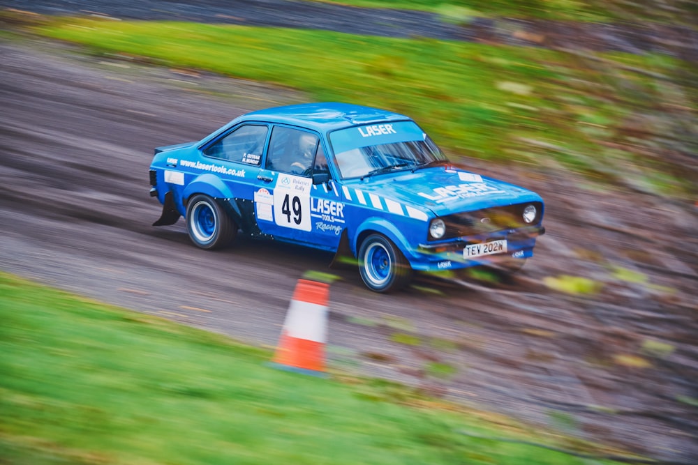 a blue car driving down a dirt road