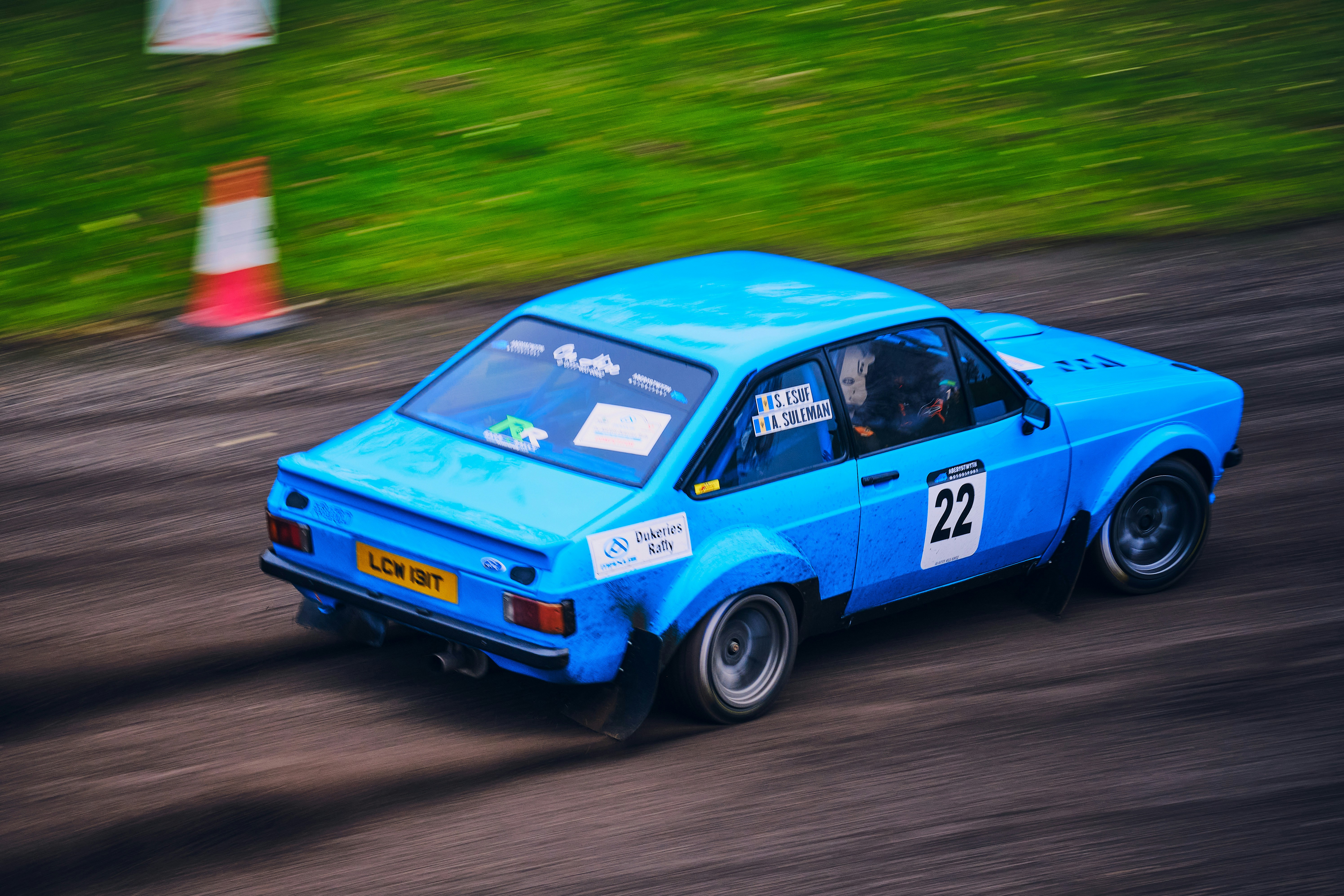a blue car driving down a dirt road
