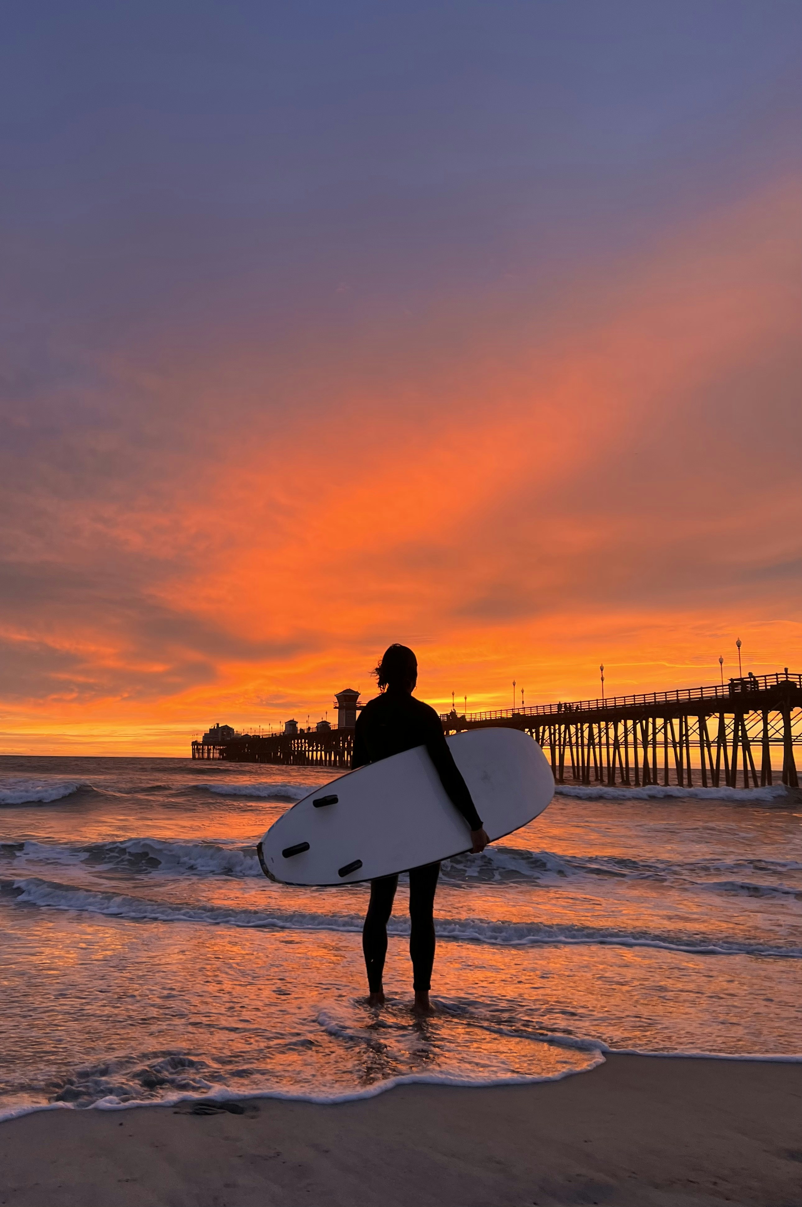 a man holding a surfboard on top of a sandy beach