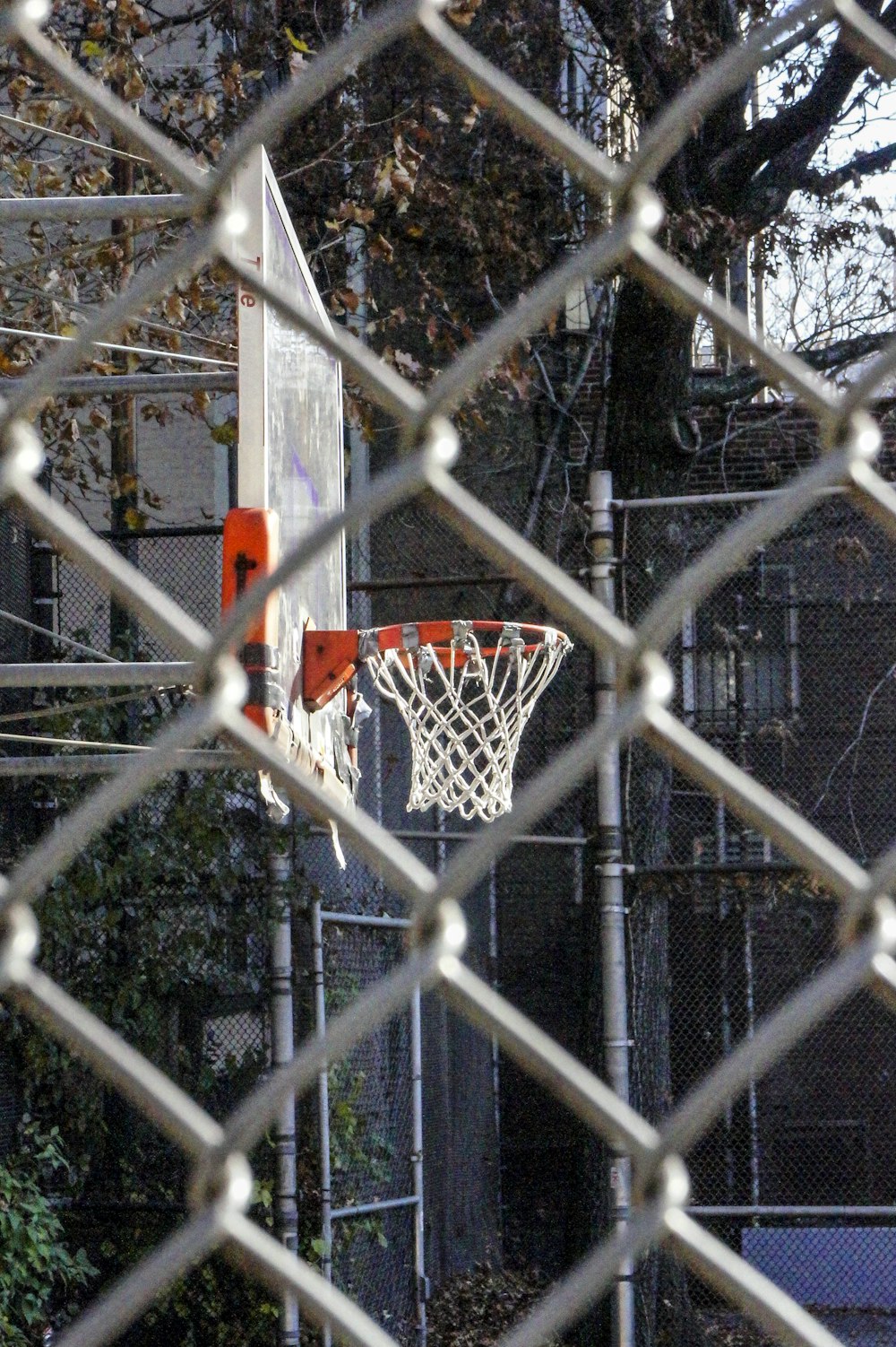 a basketball hoop is seen through a chain link fence