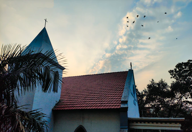 a church with a steeple and a red tiled roof