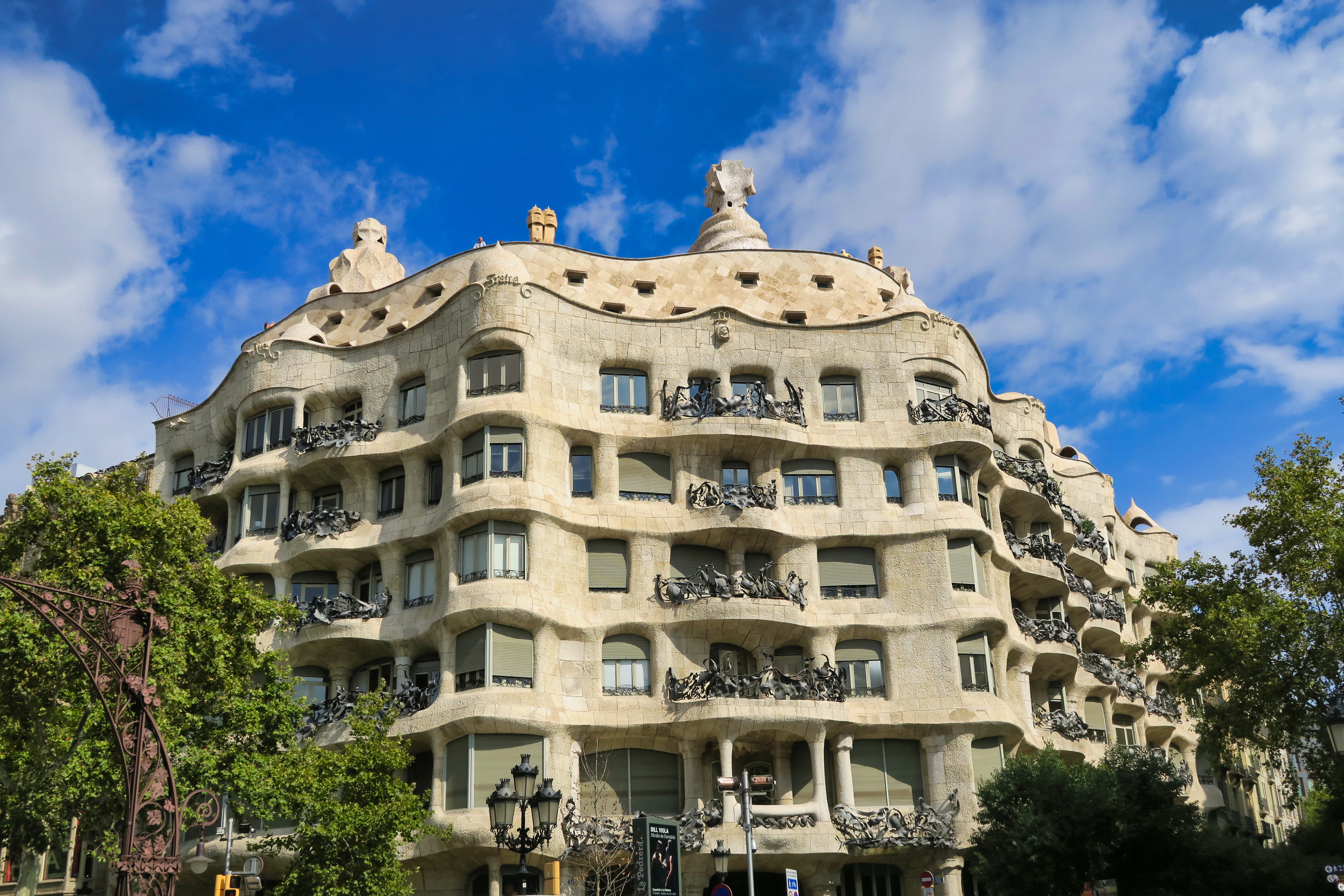 The rippling stone facade and wrought-iron balconies of Gaudi's Casa Mila, La Pedrera, in Barcelona under a blue sky