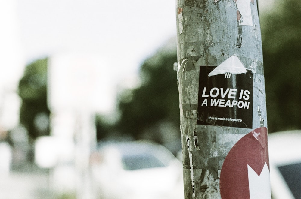 a sticker on a tree that says love is a weapon
