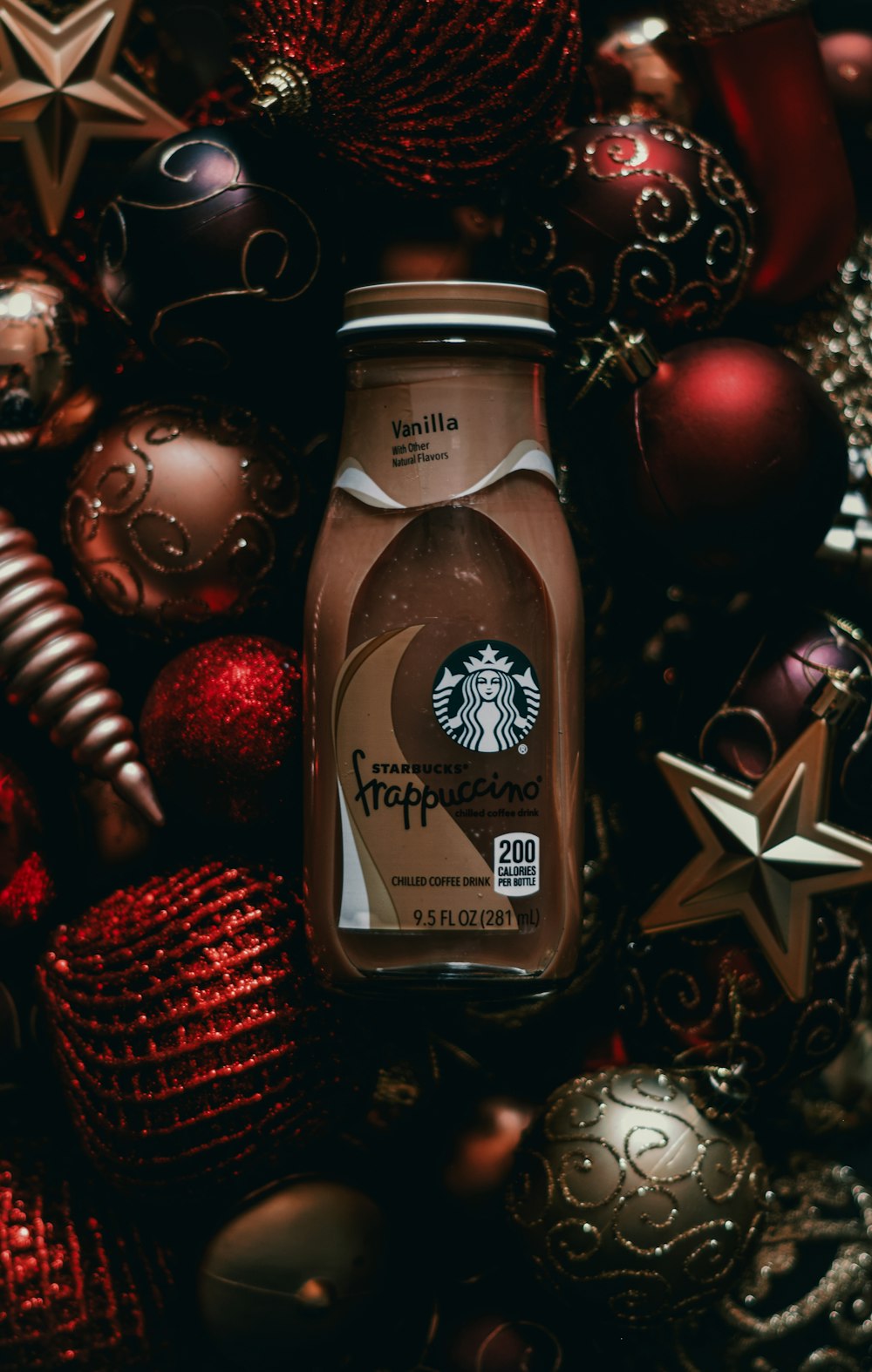 a bottle of starbucks frapple surrounded by christmas ornaments