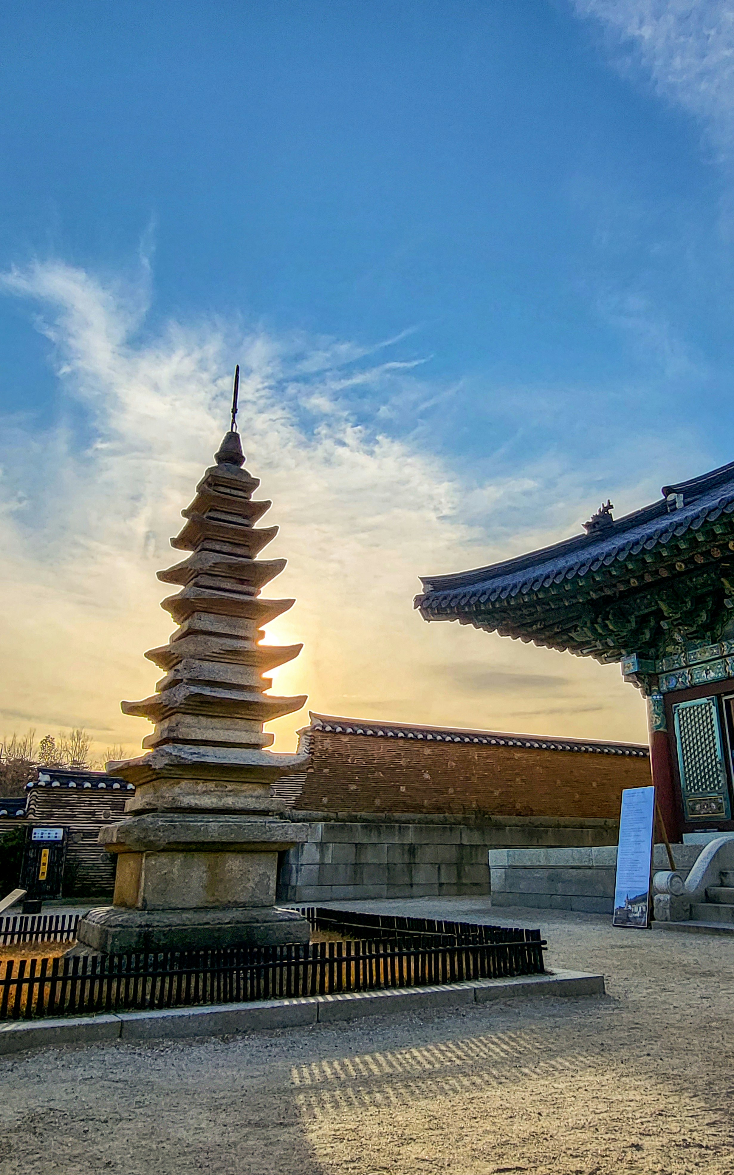 the sun is setting behind a tall pagoda