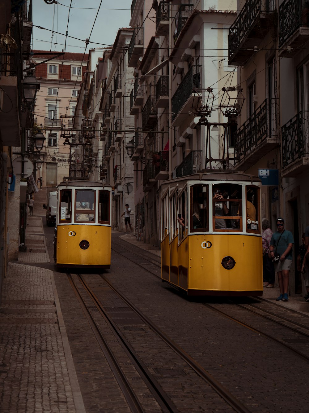 a couple of yellow trolleys traveling down a street