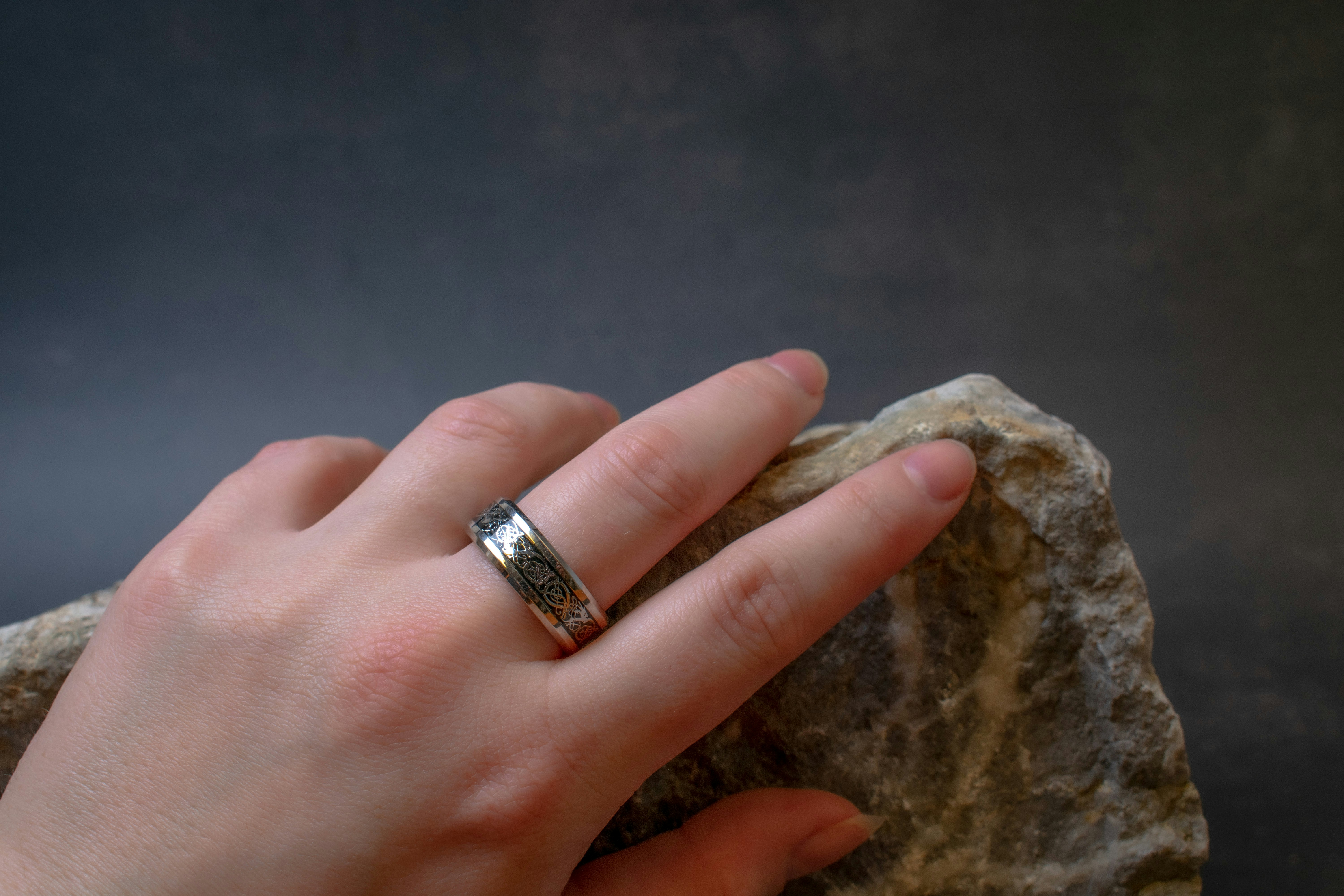Silver ring on hand on a rock with a grey background