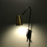 A minimalist black metal wall sconce illuminating a cozy reading nook.